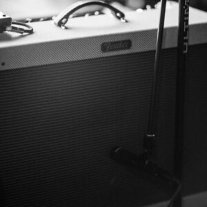 This is black and white photo of a Fender combo amp. There is also a microphone in front of it for recording.