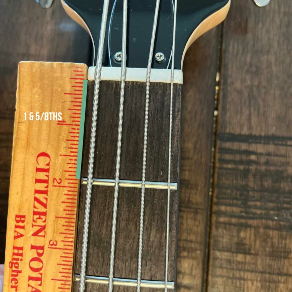 This is a picture of a bass guitar neck with a ruler next to it. This photo demonstrates the distance of the first fret on a electric bass guitar with a ruler.