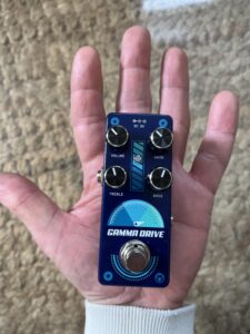 A picture of a hand holding the Pigtronix Gamma Drive guitar pedal. This picture illustrates how small the pedal is.