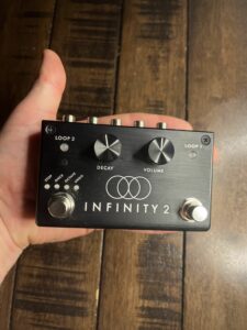A picture of a hand holding the Pigtronix Infinity 2 guitar pedal. This picture illustrates how small the pedal is.