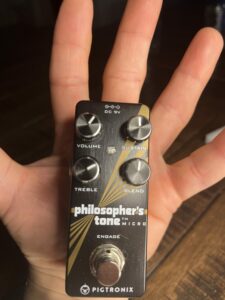 A picture of a hand holding the Pigtronix Philosopher's Tone guitar pedal. This picture illustrates how small the pedal is.