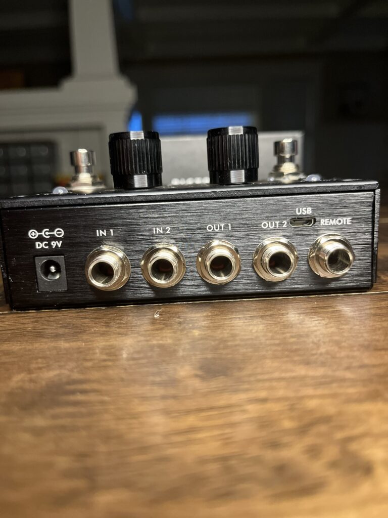 This is a picture of the the connectors on the back of a Pigtronix Infinity 2 guitar pedal. The connectors show 2 inputs, 2 outputs, a USB connection and an external foot switch connector.