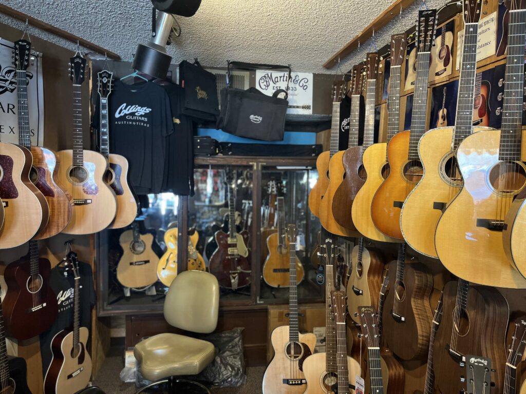 This is an original photo of the Guitar Shoppe in Laguna Beach, CA. This photo shows multiple acoustic guitars on a well. Some guitars are Martin, Guild, Collings, and Taylor.